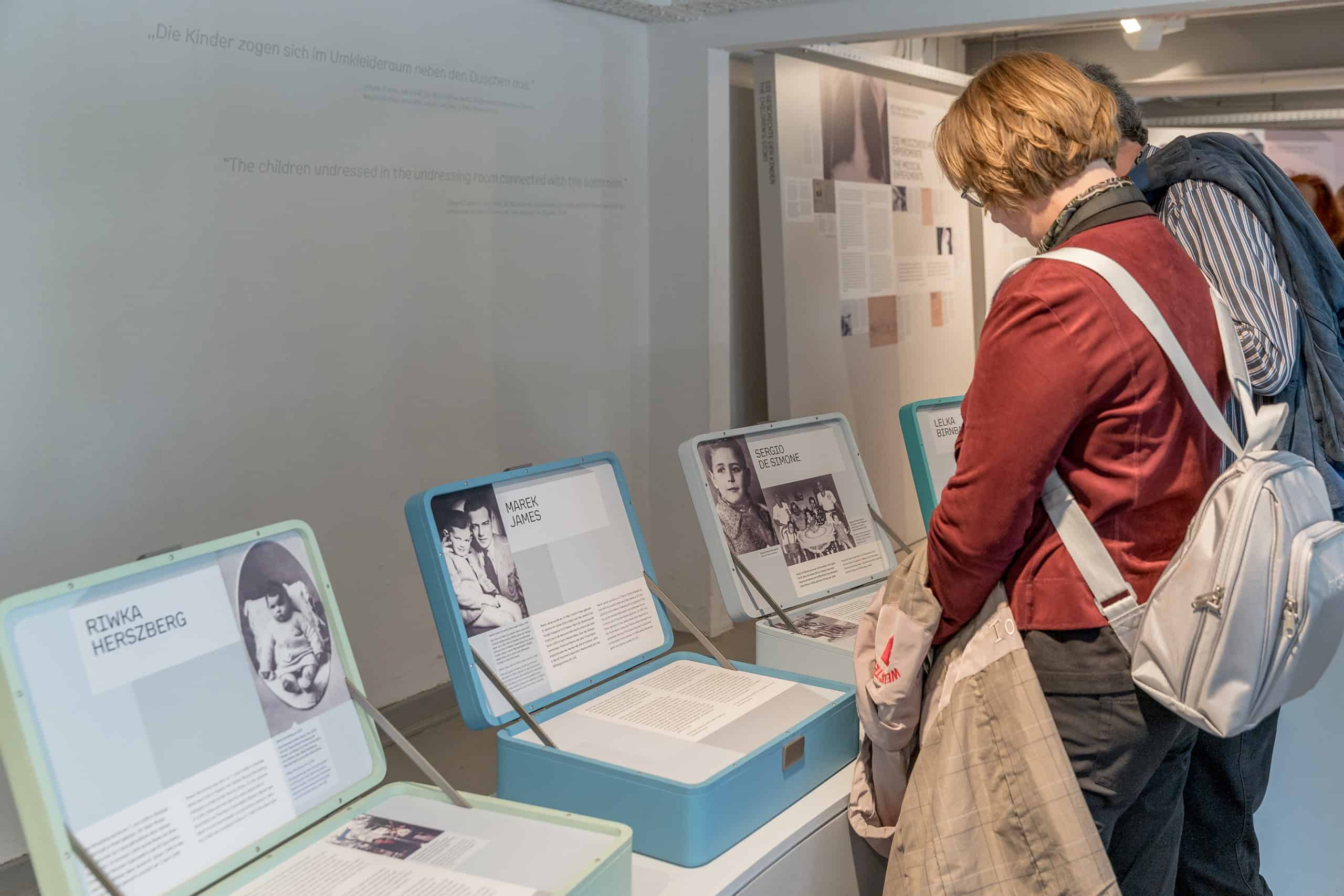 Besucher betrachten informative Ausstellungen über verschiedene Individuen in einer Gedenkstätte.