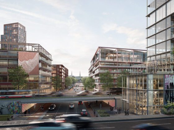 Moderne Stadt mit Glasbauten, Brücke über Straße mit Autos im Vordergrund.