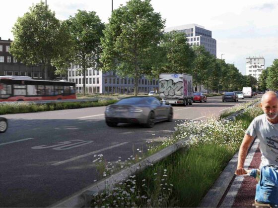 Städtische Straße mit mehreren Fahrzeugen, einem Bus, einem Radfahrer und einem Fußgänger auf einem Gehweg, der von Bäumen und Gebäuden gesäumt ist.