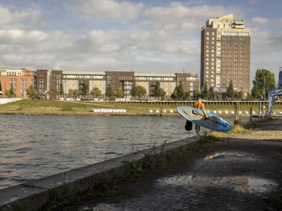 Mann mit Stand Up Paddel Board am Wasser