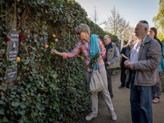 Zeitzeuginnen und Angehörige der Opfer verteilen Rosen und Steine im Rosengarten der Gedenkstätte.